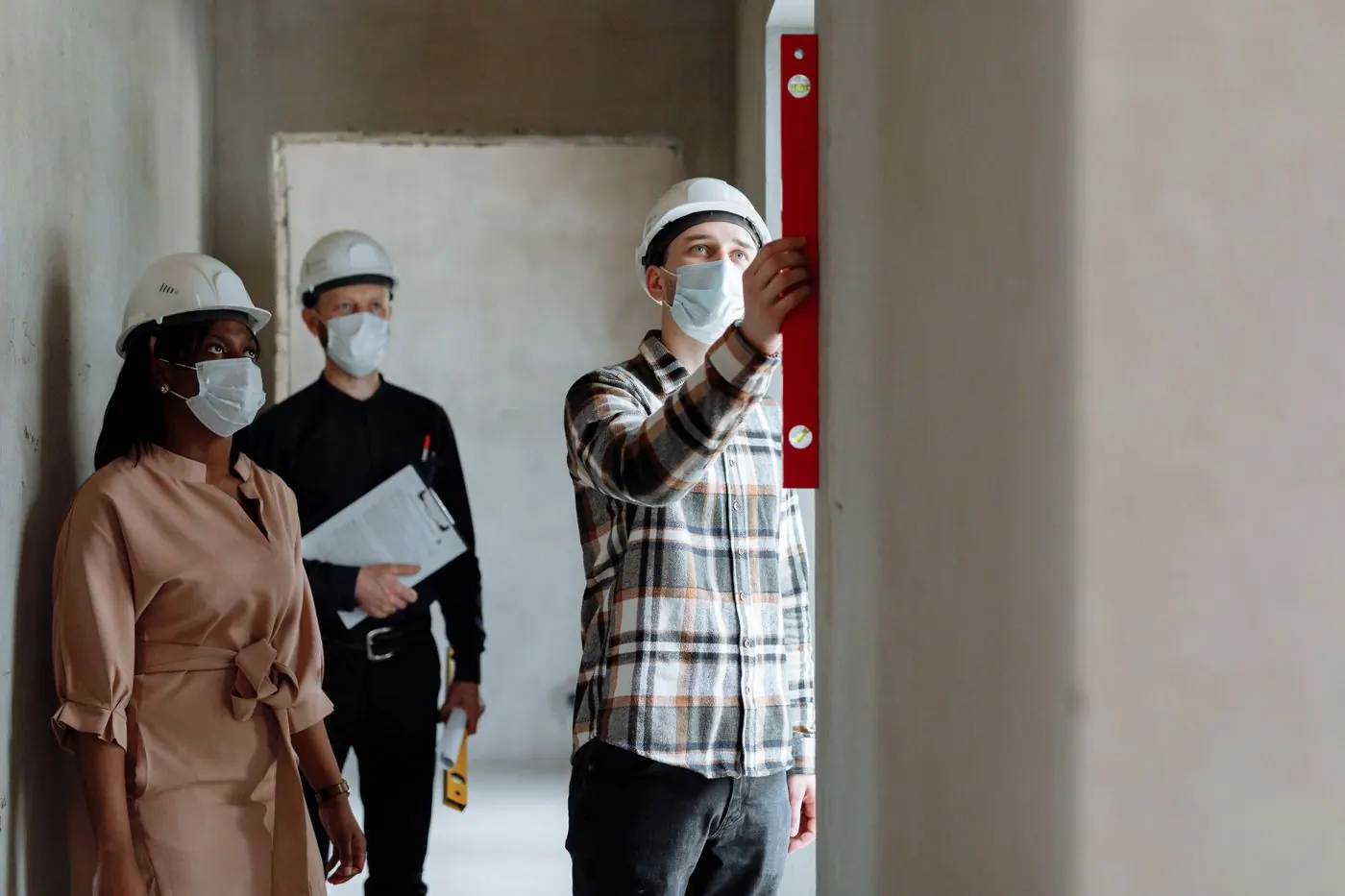 Construction workers inspecting interior work with a level